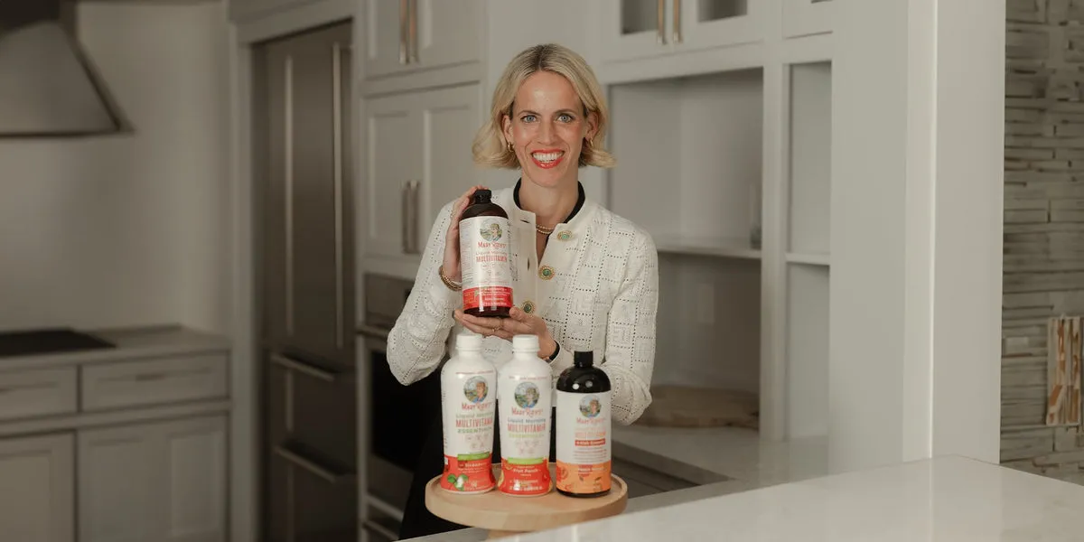 Three MaryRuth's Liquid Morning Multivitamin bottles on a wooden tray in a kitchen